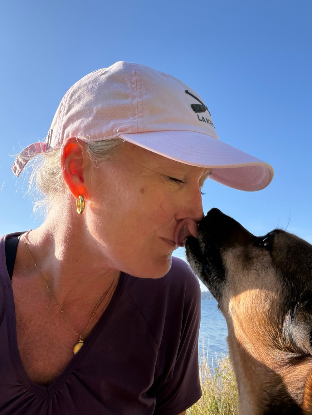 Lauren getting a nose kiss from a dog by the lake